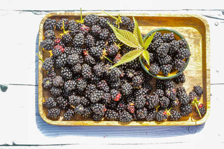Fresh and sweet blackberry with leaves on the wooden background.