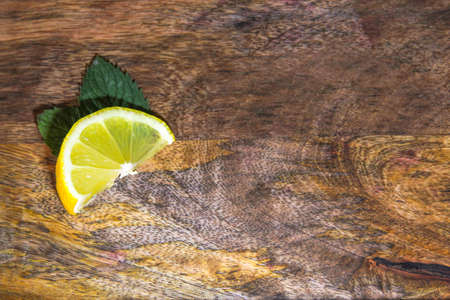 Fresh and yellow lemon with mint leaves on the wooden background.の写真素材