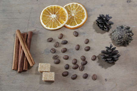 Food composition with coffee, cinnamon sticks, brown sugar, oranges and pine cones on a wooden background. Flatlay. Top view.の写真素材