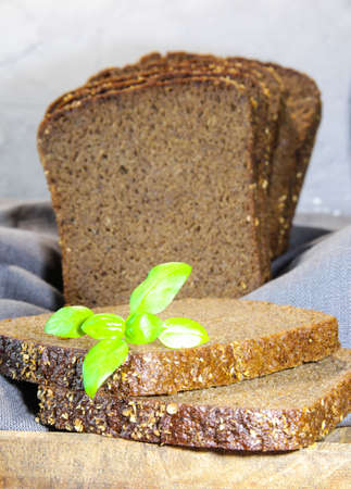 Sliced rye bread with leaf basil on cutting board. Whole grain rye bread with seeds. Vertacal...