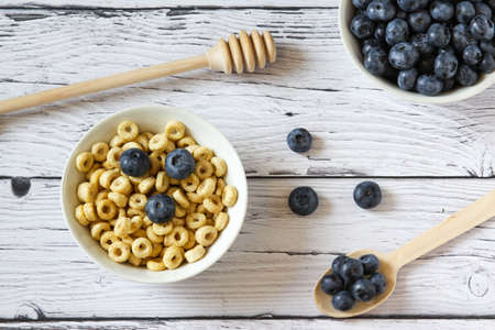 Healthy breakfast. Honey rings with blueberries in a bowl on the table wooden background. Copy space. Horizontal orientation. Top view. Flat layの写真素材