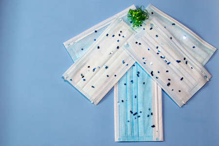 Christmas tree made out of hygienic face masks and christmas on the blue background. Christmas...