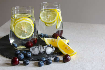Cold drinks in small bottles. Cherries and lemon lemonade or cocktail.の写真素材