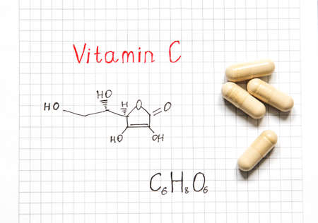 Chemical formula of Vitamin C and some pills on the white paper background. close-up. Vitamins for health. high quality photoの写真素材