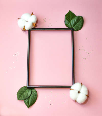 Summer modern composition. Black photo frame, green leaves and flower cotton of tree on pastel pink background. Flat lay, top view, copy space. high quality photoの写真素材