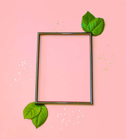 Summer modern composition. Black photo frame, green leaves on pastel pink background. Flat lay, top view, copy space. high quality photoの写真素材