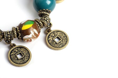A bracelet with wooden beads and china feng shui coins on a white backgroundの写真素材