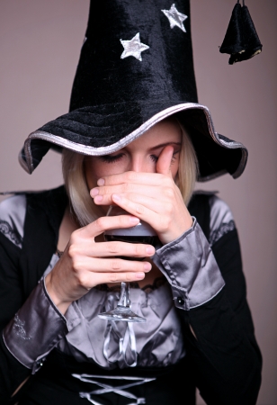 Pretty young witch in black and silver costume conjuring with a potionの写真素材