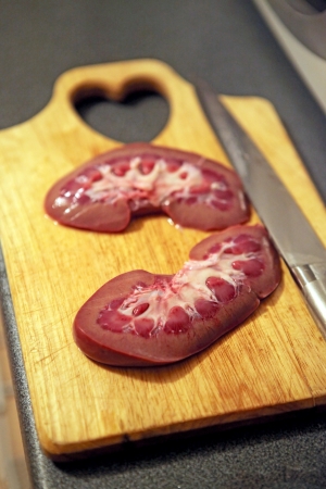 A sliced pork kidney on the cutting board before cooking.