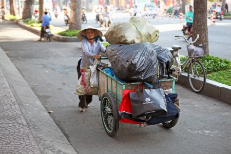 An old beggar woman with a trolley going to pass on the Waste. Saigon, Vietnam.のeditorial素材