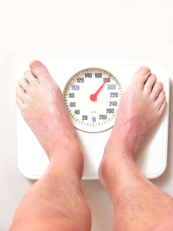 A man on the bathroom scale finds hi is to heavy and needs					