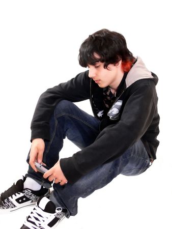 Teen boy sitting  60776		A teenage boy is sitting on the floor in the studio with his game boy on	white background.の写真素材
