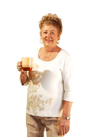 An senior woman with a coffee cup in her hand standing in a studio. の写真素材