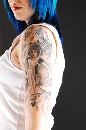 Nice tattoo on the arm of a pretty girl in a white t-shirt and bright blue hair on black background. の写真素材