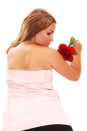 Young, lovely girl in a short pink dress with red hair, lying on the floor with a red rose, looking to the side with, on white backgroundの写真素材