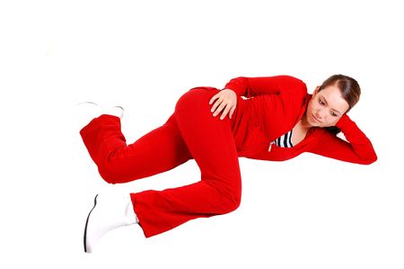 A pretty young woman in a red track suit and white boots lying in the studio on the floor and relaxing, for white background.の写真素材