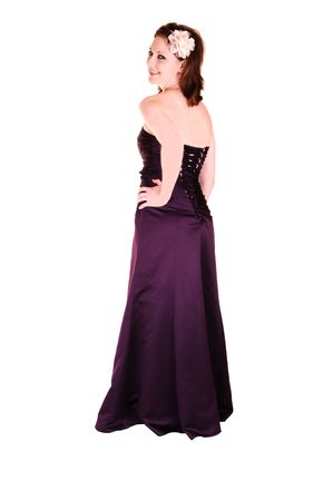 An beautiful young woman in an burgundy long evening gown standing in the  studio, looking over her shoulder for white background.の写真素材