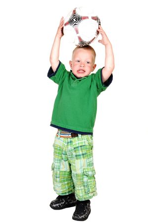 A lovely toddler standing on the floor in the studio holding up a big soccer ball, on white background.の写真素材