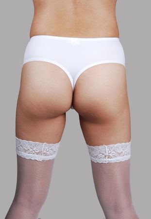 The backside of a young Chinese woman in white lingerie and stockings over white background.の写真素材