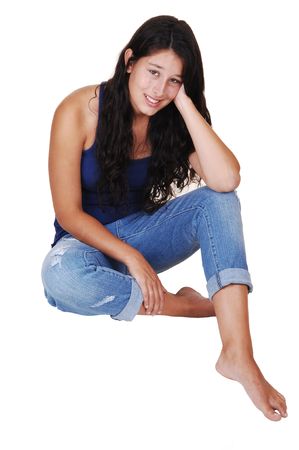A pretty young woman with long brunette hair and jeans sitting on the floor, smiling into the camera, for white background. の写真素材