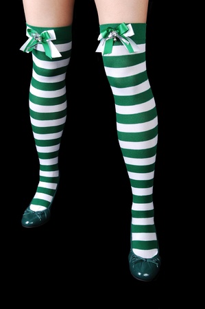The beautiful legs of a woman in green and white stripes, with green heels for black background.の写真素材