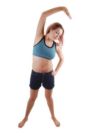 A young women in a blue sports bra and shorts standing on bare feet and doing some gymnastic, for white background.の写真素材