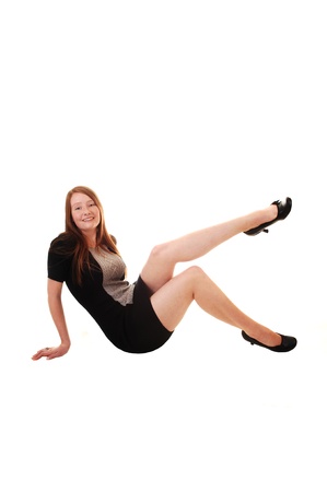 A young woman whit long red hair, a black gray dress and heels, sitting on the floor and relaxing, for white background.の写真素材