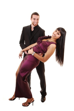 A young couple in a long burgundy dress and he in a black suit dancing in the studio over white background.の写真素材