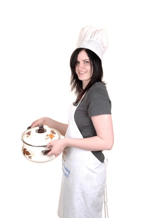 A pretty young woman, holding a cook pot, standing with an apron, black hair and a cook hat for white background.の写真素材