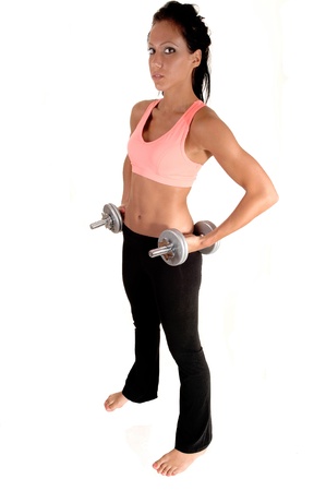 A pretty woman with dumbbells lifting, standing in the studio with barefeet, for white background.の写真素材