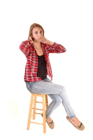 A tall pretty woman sitting on a chair in jeans and a checkered shirtfor white background.の写真素材