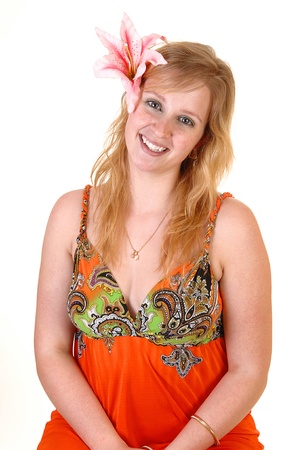 An gorgeous teenager girl in a colourful orange dress and a lily in her hairstanding in the studio with a pretty smile, for white background.の写真素材