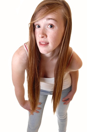 A lovely young teen girl standing and bending forward to the camera whither long brunette hair, in t-shirt and jeans for white background.の写真素材