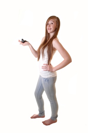 Lovely teen girl holding a black birth, in jeans and t-shirt standing bare feetin the studio with her long brunette hair, for white background.の写真素材