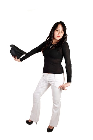 Young pretty woman in white dress pants, black sweater and high heelsholding a gray hat in her hand for white background.の写真素材
