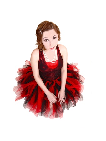 A teenage girl in an red and black ballet outfit kneeling on the floor,looking up into the camera, for white background の写真素材