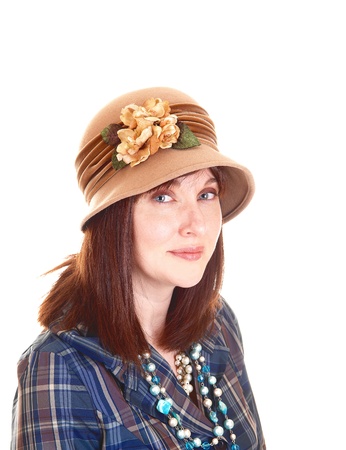 A portrait of a beautiful middle aged woman in a blue shirt and necklacewith a beige hat with flowers on, and red hair for white background の写真素材