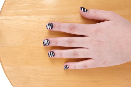 One hand from a teenage girl with polished fingernails sitting on a wood chair の写真素材