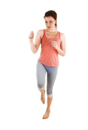 A lovely young woman running in the studio for white background in bluethighs and a pink t-shirt and bare foot の写真素材