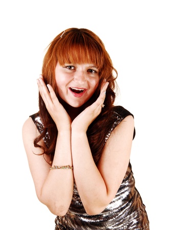 A very happy young woman, holding her head and laughing into the camera, in a evening dress with bright red hair, for white background の写真素材