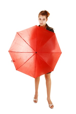 A lovely young woman in a black dress and brown leather jacket and highheels standing white background holding an red umbrella in frond of her の写真素材