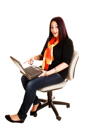 A young woman, sitting on an office chair with a laptop on her lap andfound some very interesting staff, for white background の写真素材