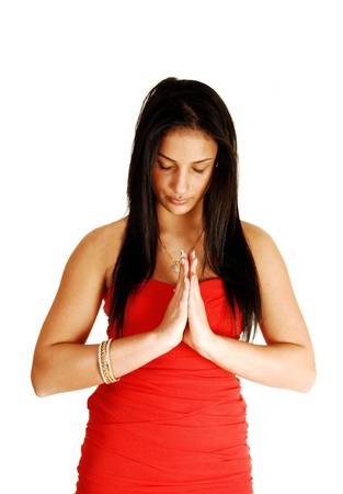 A young pretty teenage girl in a red strapless dress standing for white background, with folded hands and praying to the Lord の写真素材