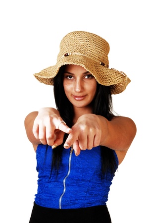 A teenager girl in a blue corset, black skirt and a straw hat standing forwhite background with her long black hair, pointing with both fingers atthe photographer の写真素材
