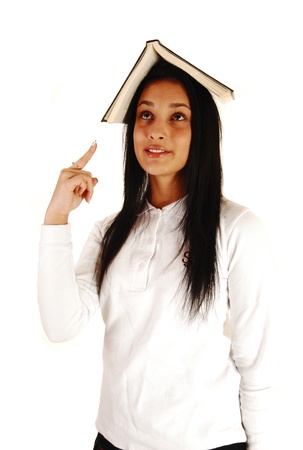 A lovely teenage girl in her school uniform with a book on top of her headstanding for white background with her long black hair の写真素材