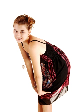 A beautiful young woman in a colorful black dress standing for white background with her hands on her knees の写真素材