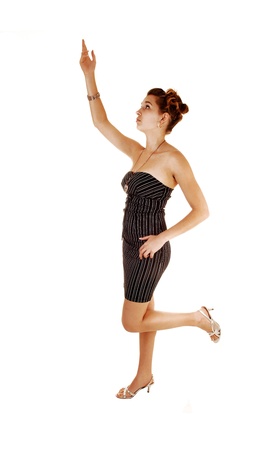 A pretty and young woman in a black dress with stripes on standing fromthe side for white background with one hand the ear, の写真素材