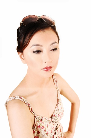 A closeup portrait of a beautiful chinese woman with sunglasses on her headand a light summer dress for white background の写真素材