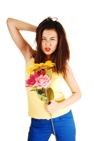 A very angry young chinese woman with some flowers in her hand, standingfor white background with an angry face, messing up her hair の写真素材