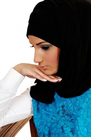 A young beautiful girl with a black headscarf and nice makeup, with herhand under her skin looking away for in closeup over white background の写真素材